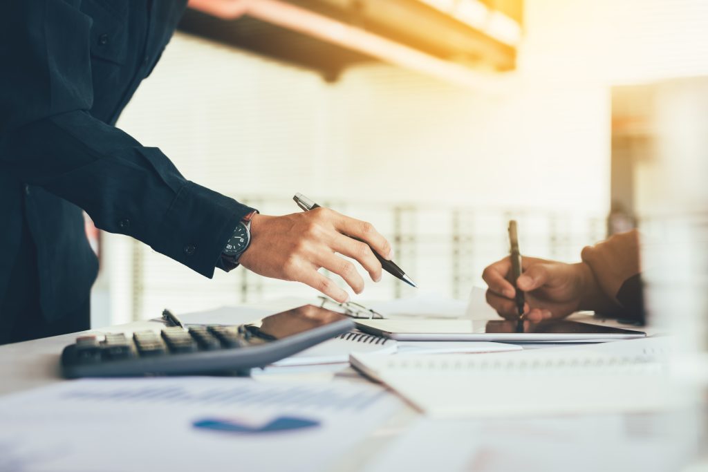 Two business people working together on desk in office room.
