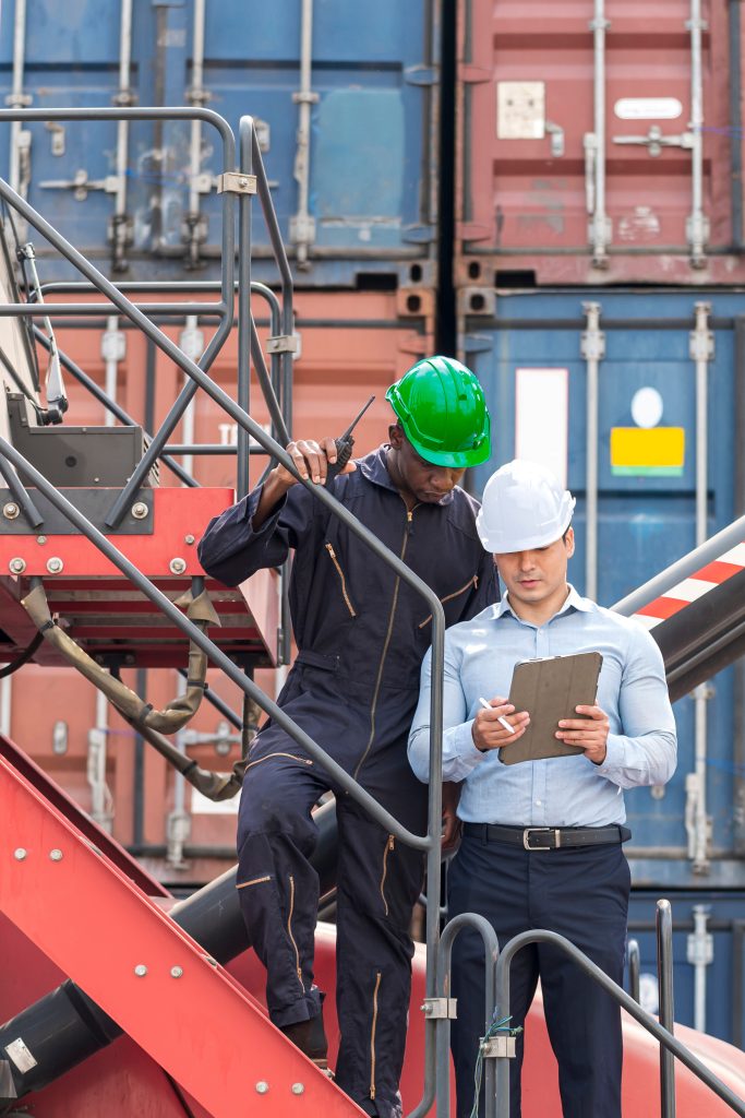 African American Environment engineer and young businessman working and discussing in shipping container in commercial transport port