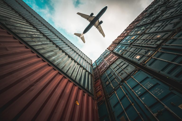 Freight airplane flying above overseas shipping container